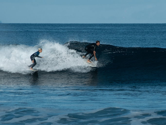 Dos personas haciendo surf en Playa Las Américas